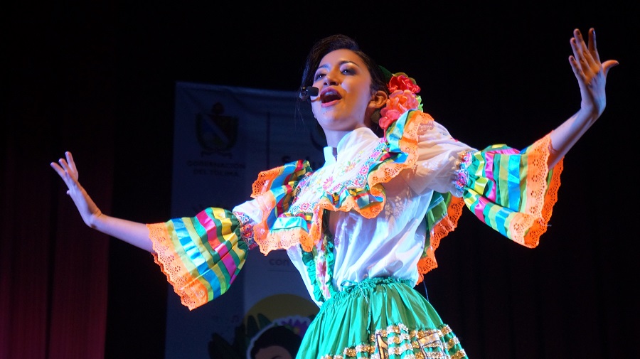 Imagen Karoll Caballero interpretando una canción usa un traje típico
